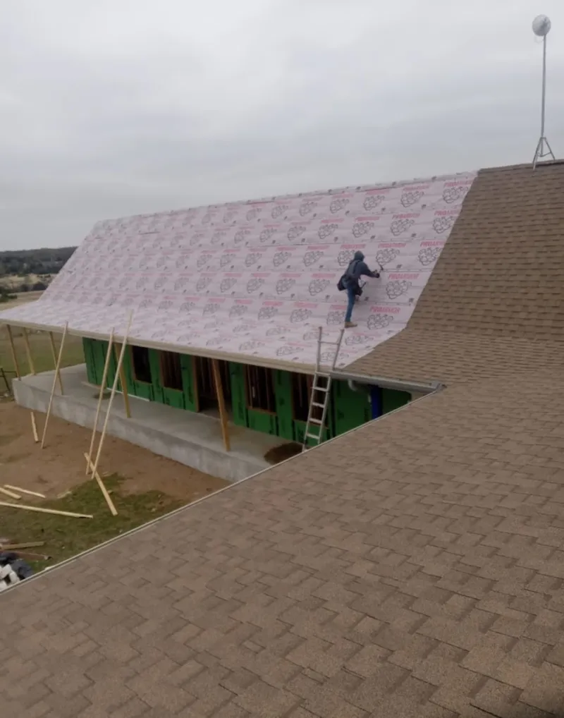 Worker preparing underlayment for a metal roof installation in Waterford